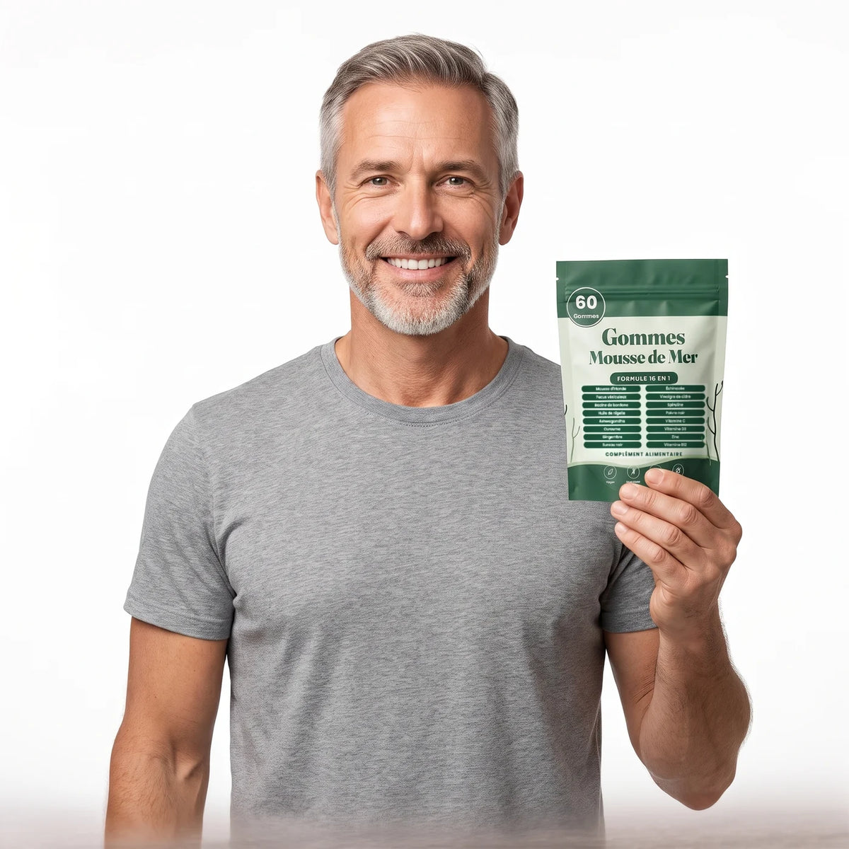 Homme de 50 ans souriant, t-shirt gris, qui tient un sachet de gommes Mousse de Mer Sarveni